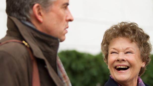 Judi Dench lacht mit einem Mann im Gespräch.