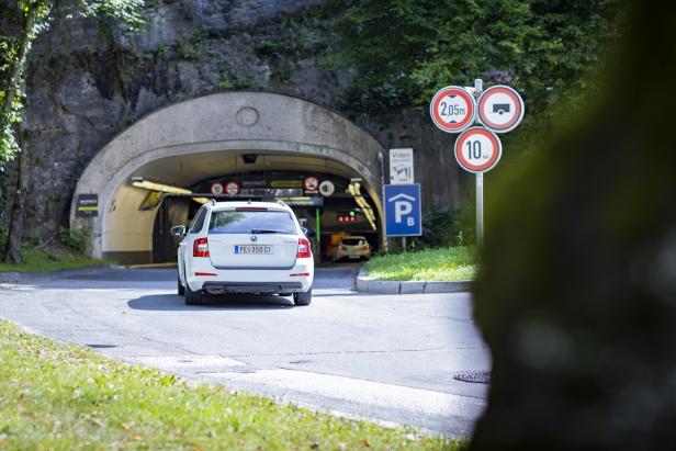Ein weißer PKW fährt in eine Tiefgarage mit Geschwindigkeitsbegrenzung und Höhenbeschränkung.