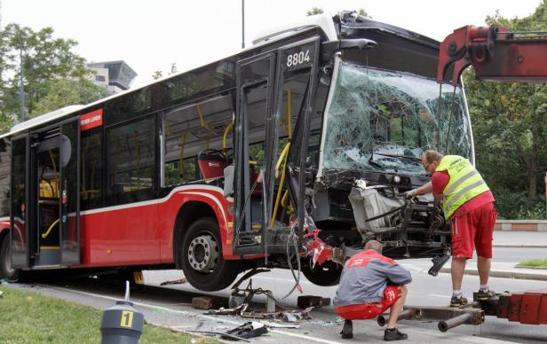 Ein schwer beschädigter Bus wird von einem Kran angehoben.