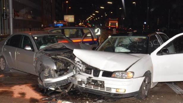 Zwei beschädigte Autos nach einem Unfall auf einer nächtlichen Straße.