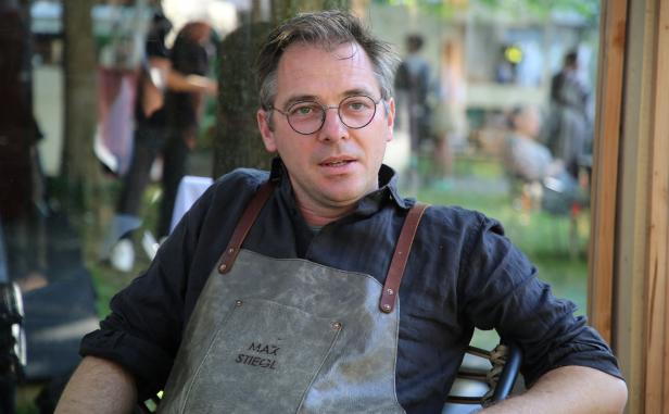 Max Stiegl sitzt mit einer Lederschürze in einem Garten.