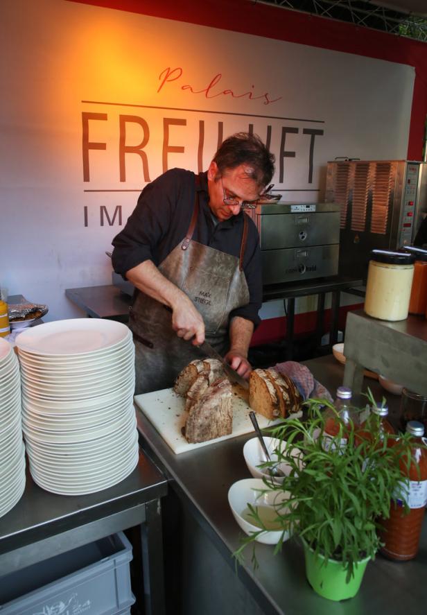 Ein Koch namens Max Stiegl schneidet Brot in einem Imbissstand des „Palais Freiluft“.