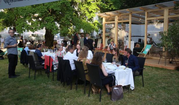 Eine Gruppe von Menschen sitzt an einer langen Tafel im Freien.