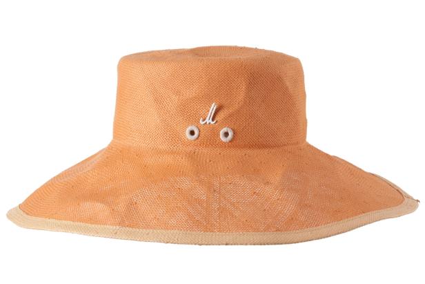 Ein orangefarbener Sonnenhut aus Stroh mit weißer Zierde.