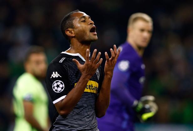 Ein Fußballspieler in einem schwarz-weißen Trikot gestikuliert auf dem Spielfeld.