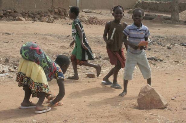 Eine Gruppe Kinder spielt im Freien in einem ländlichen Gebiet.