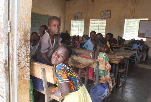 Eine Gruppe afrikanischer Schulkinder sitzt in einem Klassenzimmer.