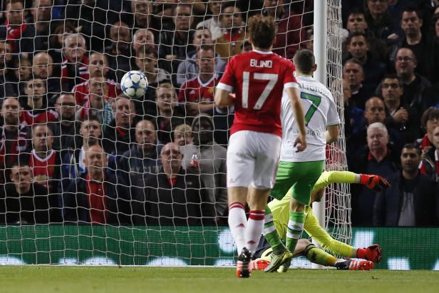 Ein Fußballspiel mit Spielern vor einem Tor und vielen Zuschauern im Hintergrund.