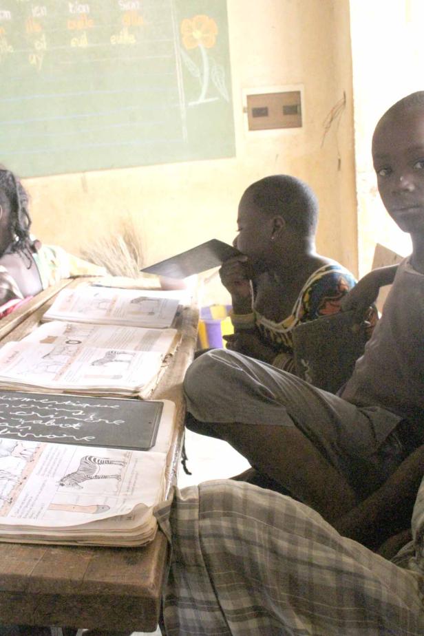 Kinder sitzen in einem Klassenzimmer an ihren Schreibtischen.