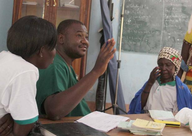 Ein Arzt erklärt einer älteren Frau etwas, während eine andere Person zuhört.