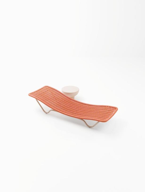 Eine orangefarbene Miniatur-Sonnenliege steht neben einem kleinen, runden Tisch.