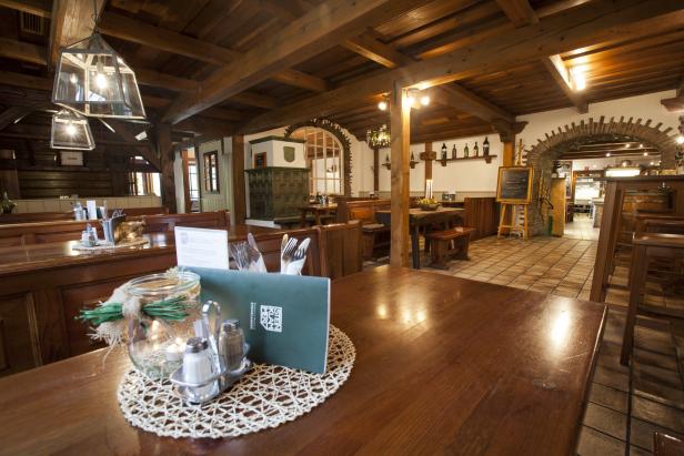 Innenansicht eines traditionellen bayerischen Restaurants mit Holzbalken und gedeckten Tischen.