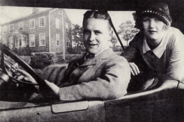 F. Scott Fitzgerald und Zelda Fitzgerald in einem Auto vor einem Haus.