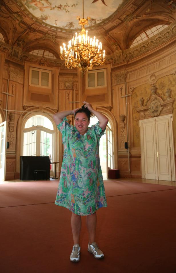 Eine Frau steht in einem prächtigen Saal mit einem großen Kronleuchter.