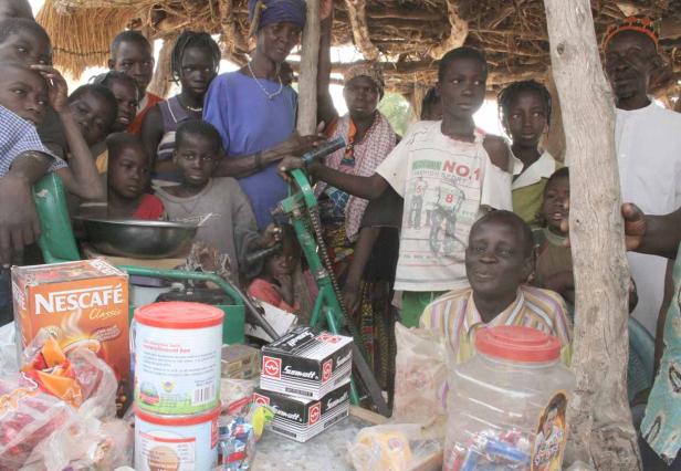 Eine Gruppe von Menschen steht um einen Tisch mit Lebensmitteln und anderen Gütern.