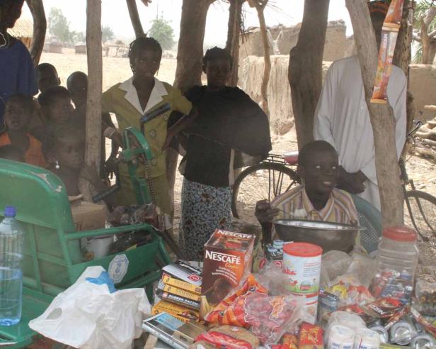 Eine Gruppe von Menschen steht an einem Verkaufsstand im Freien.