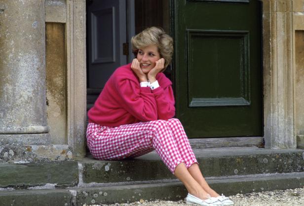 Diana, Prinzessin von Wales, sitzt lächelnd auf einer Steintreppe.