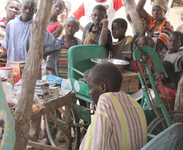 Eine Gruppe von Kindern steht um einen improvisierten Verkaufsstand im Freien.