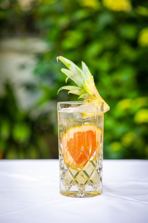 Ein erfrischendes Getränk mit Grapefruit und Ananasgarnitur auf einem Tisch.