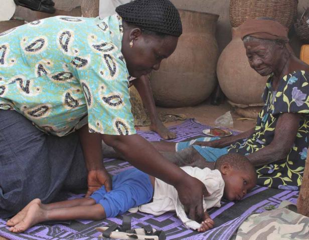 Eine Frau behandelt ein Kind, während eine ältere Frau daneben sitzt.
