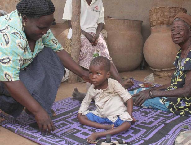 Eine Frau kümmert sich um ein Kind, während zwei weitere Frauen im Hintergrund sitzen.