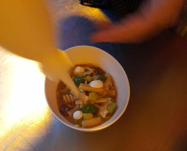 Eine Schüssel mit Nudeln, Gemüse und kleinen Mozzarella-Kugeln wird angerichtet.
