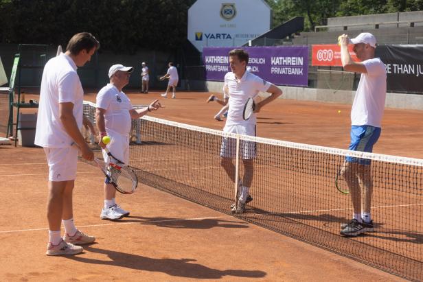 Mehrere Tennisspieler stehen auf einem Sandplatz und unterhalten sich.
