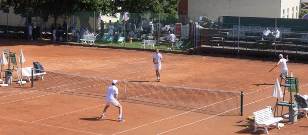 Zwei Männer spielen Tennis auf einem Sandplatz.