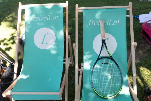 Ein Tennisschläger liegt auf einem Liegestuhl mit dem Logo von freizeit.at.