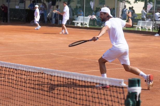 Ein Tennisspieler schlägt den Ball auf einem Sandplatz.