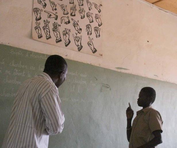 Ein Lehrer und ein Schüler kommunizieren in einem Klassenzimmer mit Gebärdensprache.