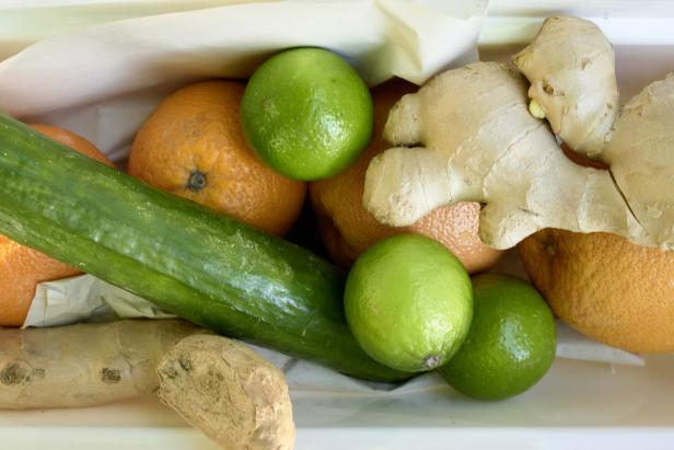 Eine Gurke, Limetten, Mandarinen und Ingwer liegen in einer weißen Schale.