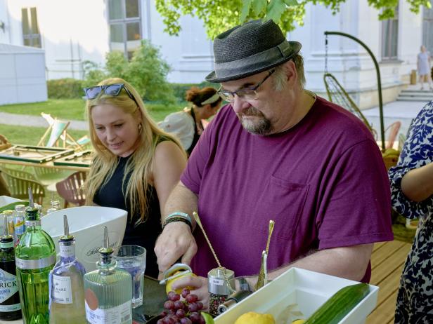 Ein Mann bereitet an einem Tisch mit einer Frau Cocktails zu.