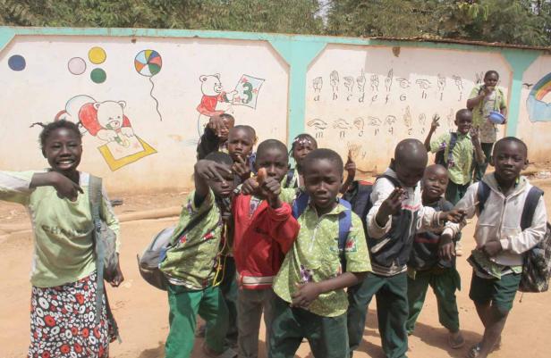 Eine Gruppe Schulkinder posiert vor einer bemalten Mauer.