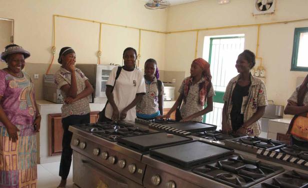 Eine Gruppe Frauen steht in einer Küche vor einem großen Herd.