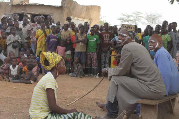 Eine Gruppe von Menschen versammelt sich im Freien, einige mit traditioneller Gesichtsbemalung.