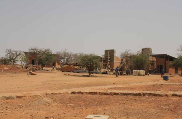 Bauarbeiter sind auf einer Baustelle in einer trockenen, staubigen Gegend tätig.