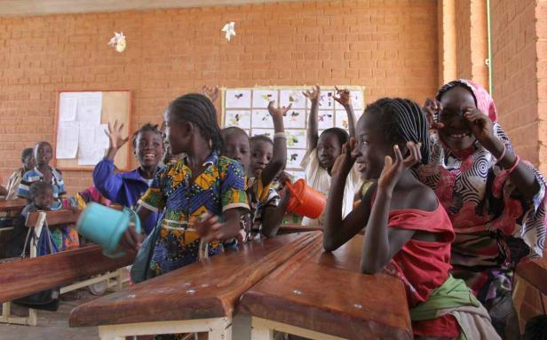 Eine Gruppe afrikanischer Kinder spielt und lacht in einem Klassenzimmer.