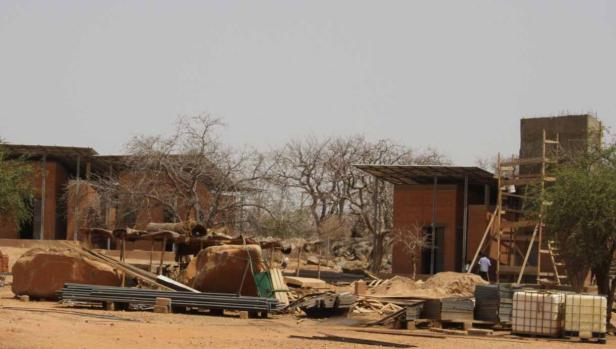 Eine Baustelle mit roten Backsteingebäuden und Baumaterialien im Freien.