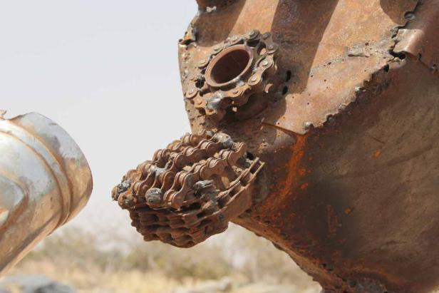 Eine Skulptur aus rostigem Metall und Ketten vor einem unscharfen Hintergrund.