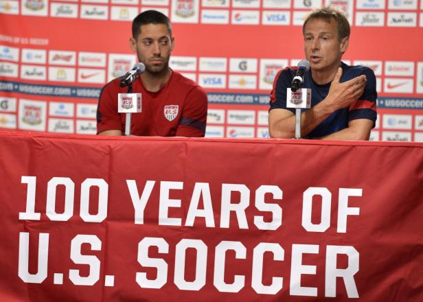 Zwei Männer sitzen an einem Tisch mit der Aufschrift „100 Years of U.S. Soccer“.