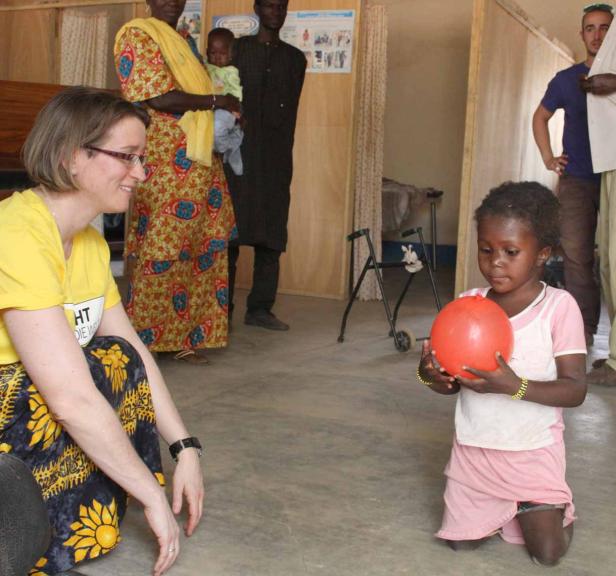 Ein kleines Mädchen kniet und hält einen roten Ballon, während eine Frau ihr gegenüber sitzt.