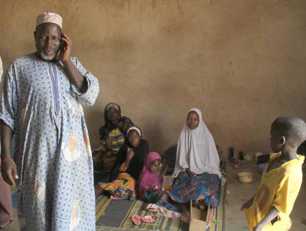 Eine Gruppe von Menschen sitzt in einem Raum auf einer Matte.