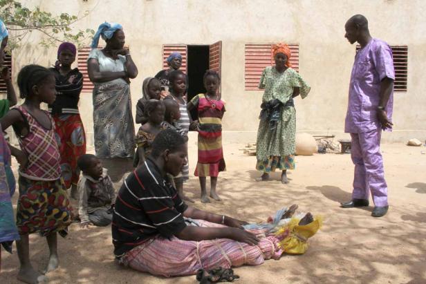 Eine Gruppe von Menschen versammelt sich im Freien vor einem Gebäude.
