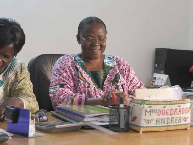 Eine Frau sitzt an einem Schreibtisch und lächelt.