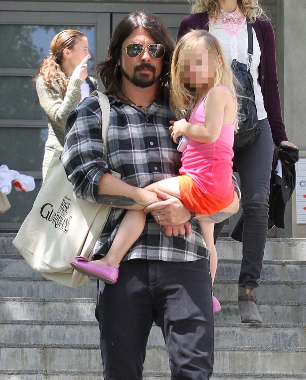 Dave Grohl trägt seine Tochter auf dem Arm, mit einer Tasche des Films „Rise of the Guardians“.