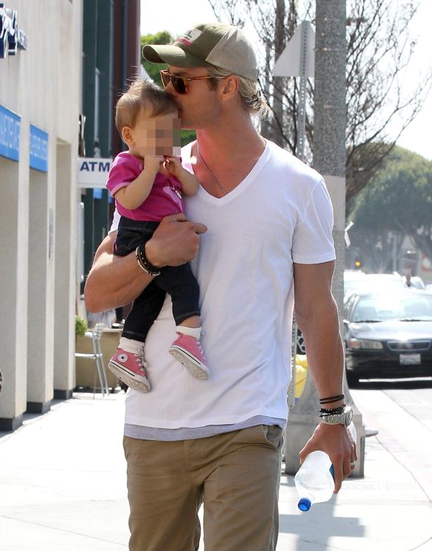 Chris Hemsworth trägt seine Tochter auf dem Arm und gibt ihr einen Kuss.