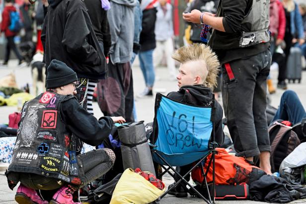 Eine Gruppe junger Leute mit Punk-Frisuren sitzt und steht im Freien.