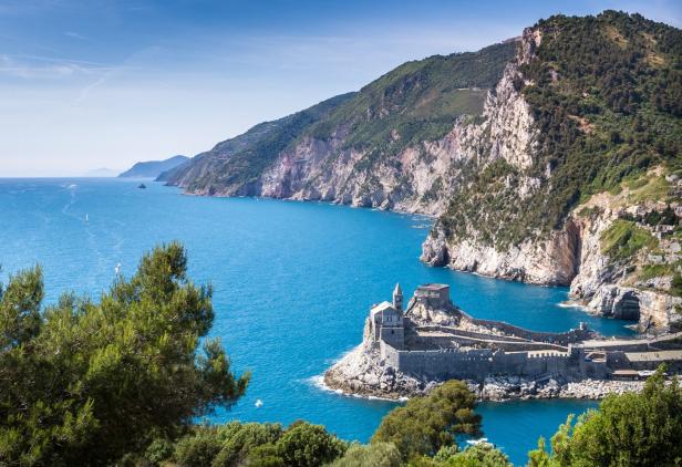 Blick auf die Kirche San Pietro in Porto Venere, Italien, umgeben von blauem Meer und felsiger Küste.
