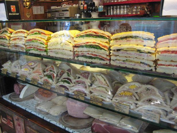 Eine Auslage mit verschiedenen belegten Broten und Tramezzini in einem Geschäft.